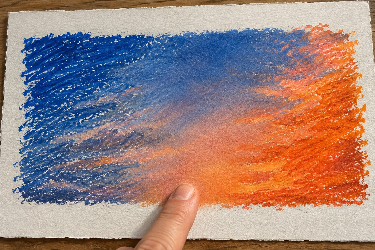 Illustrative close-up of blue and orange oil-pastel-style marks with a softly rubbed transition